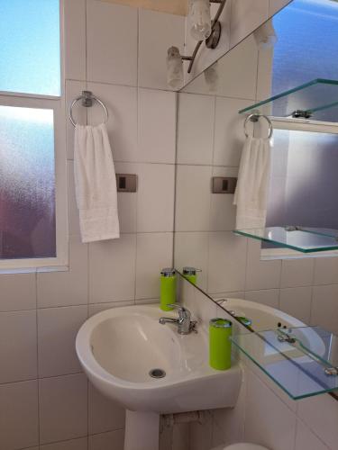 een witte badkamer met een wastafel en een spiegel bij House Patagonia I in Coihaique