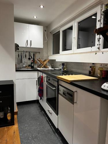 una cocina con armarios blancos y encimeras negras en Studio cosy en Bruselas
