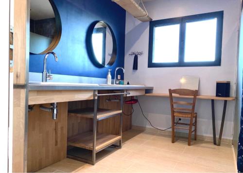 een badkamer met een wastafel en 2 spiegels bij L’écrin des bois in Mansac