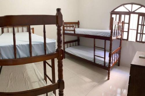 a bedroom with two bunk beds and a table at Casa Excelente Praia Grande in Fundão