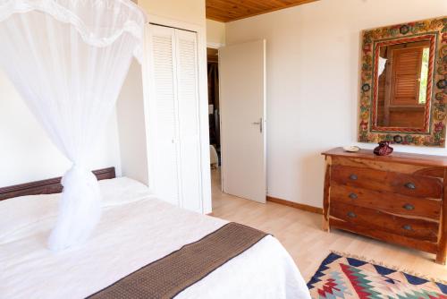 a bedroom with a bed and a dresser and a mirror at Villa Mawali in Sainte-Anne