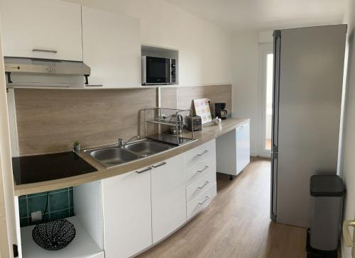 uma cozinha branca com um lavatório e um micro-ondas em Azur em Toulouse