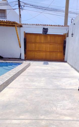 a garage with a wooden door and a swimming pool at Residencia Isidora - Casa de Playa in Punta Hermosa