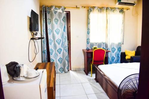 um quarto com uma cama, uma secretária e uma janela em Appartement/Studio meublé a Bangui em Bangui