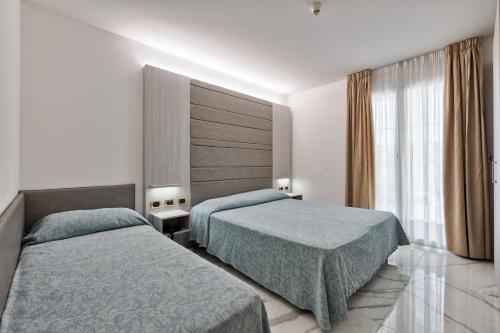 Habitación de hotel con 2 camas y ventana en Columbus Dependance, en Lignano Sabbiadoro