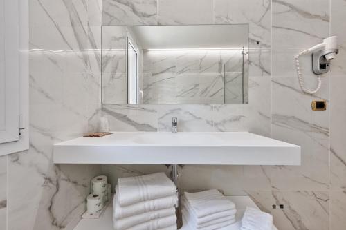 Baño blanco con lavabo y espejo en Columbus Dependance, en Lignano Sabbiadoro