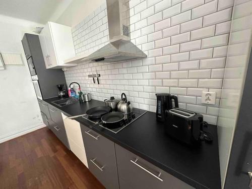 a kitchen with a black counter top and white tiles at Iridsbo Lockarp gård in Malmö