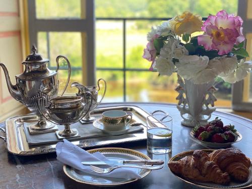 una mesa con una bandeja de comida y un jarrón con flores en Château de La Tour en Brenne, en Rivarennes