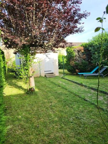 un patio con un árbol y un cobertizo blanco en Maison de campagne avec jardin près du Périgord, en Mansac