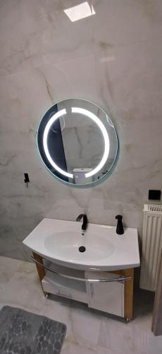 W łazience znajduje się lustro i biała umywalka. w obiekcie Casa Montagna w mieście Florina