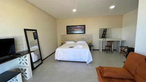 ジャグァルナにあるHospedaria das Pedras Sua Casa de Férias Litoral Santa Catarinaのベッドルーム(ベッド1台、ソファ、テレビ付)