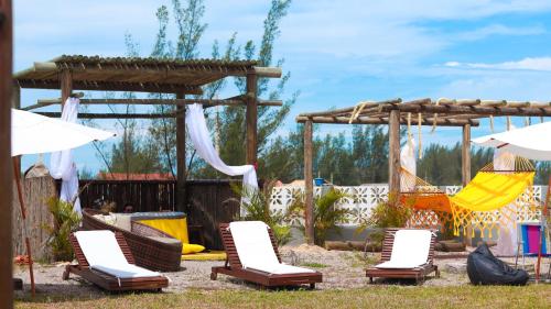 a group of chairs and umbrellas in a yard at Hospedaria das Pedras Sua Casa de Férias Litoral Santa Catarina in Jaguaruna