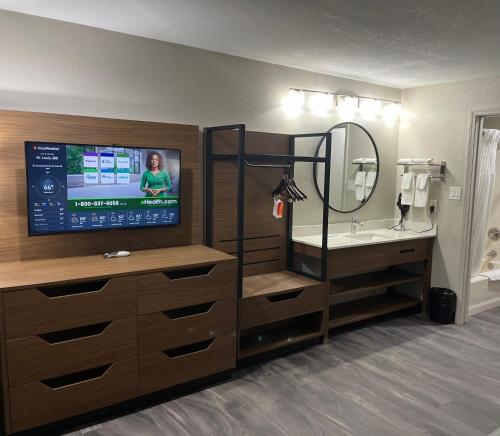 y baño con TV, lavabo y espejo. en Quality Inn & Suites Near White Sands National Park, en Alamogordo
