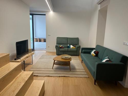 a living room with two green couches and a tv at Casa da Calvaria in Calvária