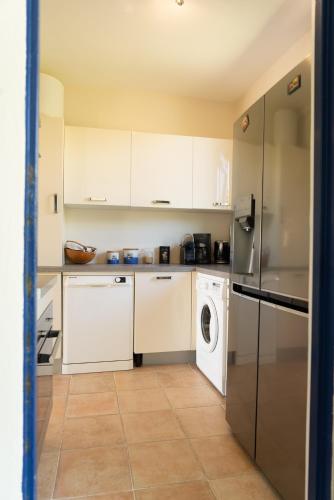 a kitchen with white cabinets and a washer and dryer at Villa Mawali in Sainte-Anne
