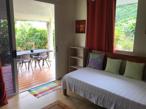 a bedroom with a bed and a balcony with a table at FARE TITAINA in Hauru