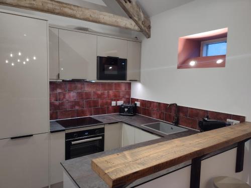 a kitchen with white cabinets and a counter top at The Cow Byre - Cotswold retreat with hot tub in Dursley