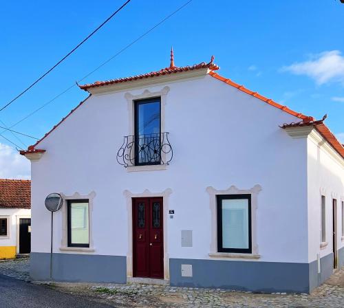 a white house with a red door and a balcony at Casa da Calvaria in Calvária