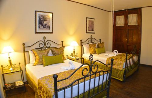 a bedroom with two beds and two lamps and a door at Hotel Los Balcones Leon in León
