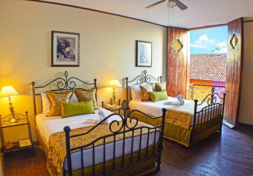 a bedroom with two beds and a window at Hotel Los Balcones Leon in León