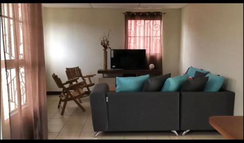 ein Wohnzimmer mit einem Sofa und einem TV in der Unterkunft Kami Hostel, Ciudad El Doral in Managua