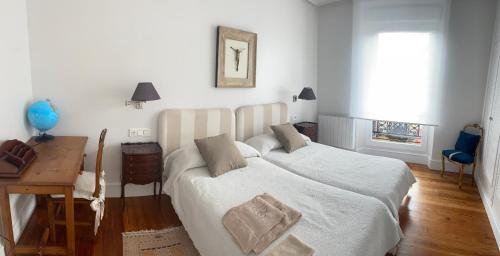 Habitación blanca con cama, escritorio y ventana en Caprichoso apartamento en zona romántica en San Sebastián