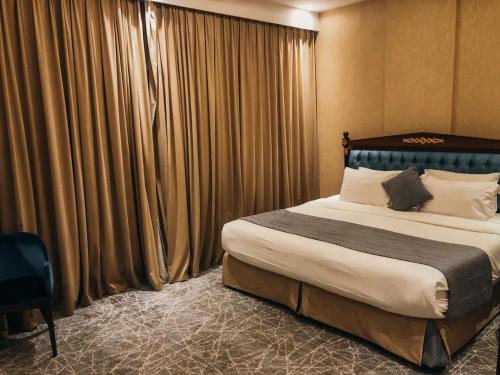 فندق فيلي Filly Hotel في حائل: غرفة نوم بسرير كبير وستائر