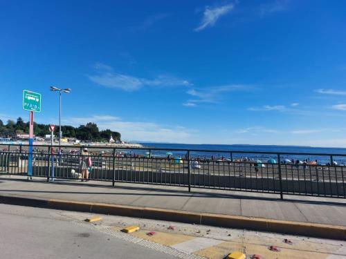 a person walking on a sidewalk near the beach at Departamento con vista al mar en Puerto Montt in Puerto Montt