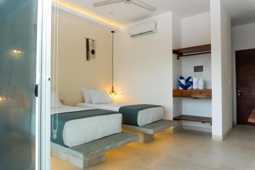 a bedroom with two beds and a glass door at Kanté Hotel - Downtown Tulum in Tulum