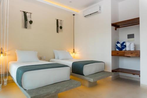 two beds in a room with white walls at Kanté Hotel - Downtown Tulum in Tulum