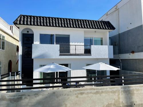 a white building with two umbrellas in front of it at House on The Beach in Los Angeles