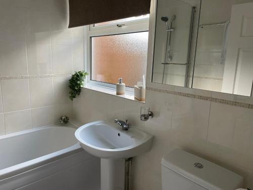 a white bathroom with a sink and a bath tub at Central Blue Holiday Home. in Bridlington