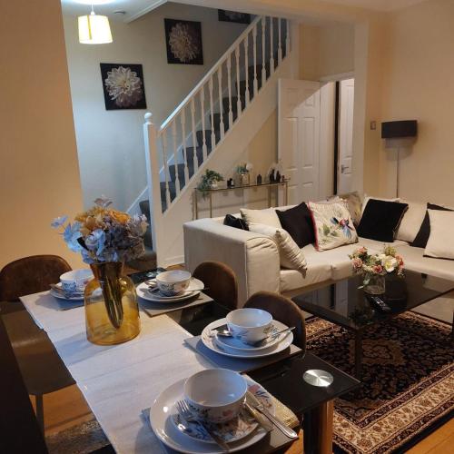 una sala de estar con una mesa con platos y flores. en Three Bed House with free on-site parking Sleeps 5 en Warrington