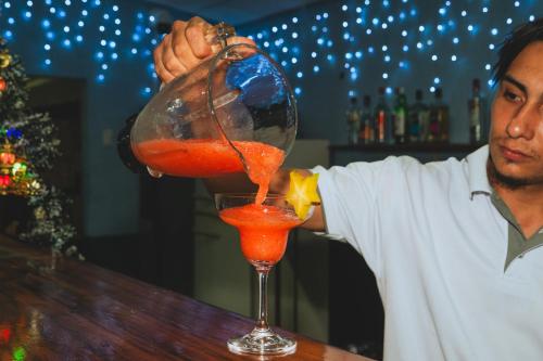 a man standing at a bar making a drink at Hotel El Cocobolo Food&Rest Room 4 B&B WiFi AC Pkg Free Swimmingpool in Liberia