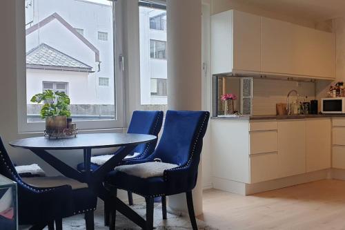 uma cozinha com uma mesa e cadeiras azuis num quarto em Niklas Ålesund City Center Apt. (sleep: 3 pers). em Ålesund