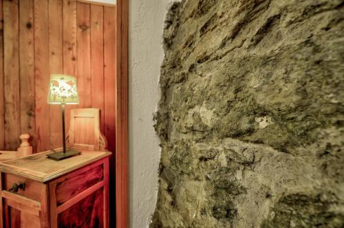 eine Lampe auf einem Tisch neben einer Steinmauer in der Unterkunft Maison Chasseur Alpine Design Lodge in Champoluc