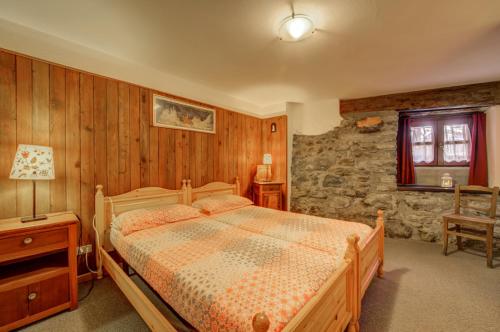 a bedroom with a bed and a stone wall at Maison Chasseur Alpine Design Lodge in Champoluc