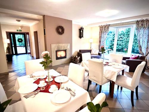 comedor con mesas y sillas blancas y chimenea en Pensjonat Rondo, en Września