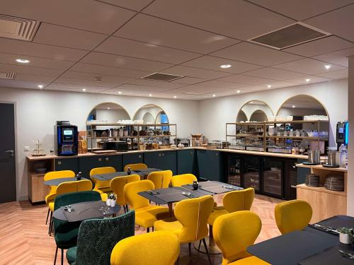 une salle à manger avec des tables et des chaises jaunes dans l'établissement Hotel Le Quercy - Sure Hotel Collection by Best Western, à Brive-la-Gaillarde