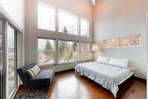 a bedroom with a bed and a chair and windows at Spokane River Retreat in Coeur d'Alene
