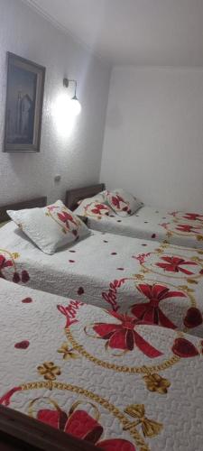 1 dormitorio con 2 camas con flores rojas. en Hotel Costa norte en Iquique