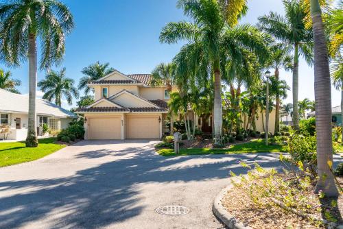 a house with palm trees in front of a driveway at Villa Hibiscus-Waterfront-Punta Gorda FL in Punta Gorda
