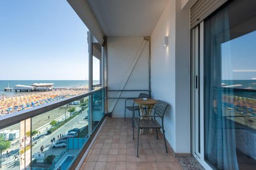 a balcony with a table and chairs and a view of the beach at Hotel Columbus in Lignano Sabbiadoro
