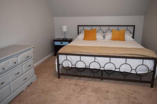 格林維爾的住宿－Home In Greenville 4 bedrooms, 4 beds, 2 baths，一间卧室配有带橙色枕头和梳妆台的床