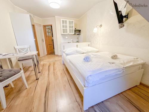 a bedroom with a white bed and a table and chair at Willa Michałówka in Zakopane