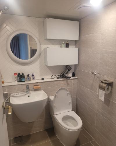 een badkamer met een wastafel, een toilet en een spiegel bij Gyeongdo CC and Ocean view in Yeosu