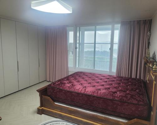 een bed in een kamer met een groot raam bij Gyeongdo CC and Ocean view in Yeosu