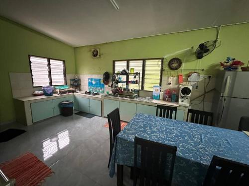 cocina con mesa y cocina con paredes verdes en Homestay Hjh Rokiah, F.Tementi, 