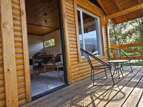 un porche con mesa y sillas en una cabaña en Cabañas Entre Cumbres en Moquehue