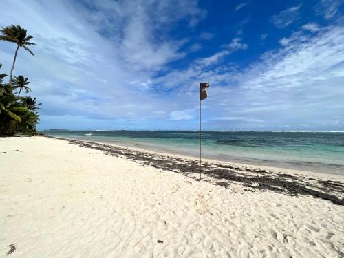 a beach with a sign in the sand and the ocean at Villa Mawali in Sainte-Anne